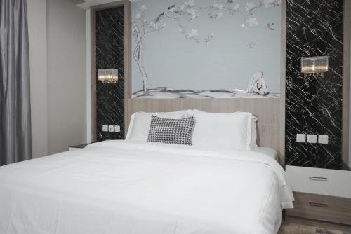 a bedroom with a white bed and a picture on the wall at Swiss In Park Tabuk in Tabuk