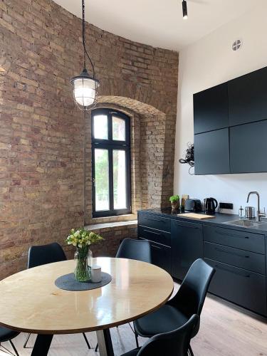 a kitchen with a table and chairs and a brick wall at Apartamenty Wieża - Tower Apartments in Wałcz