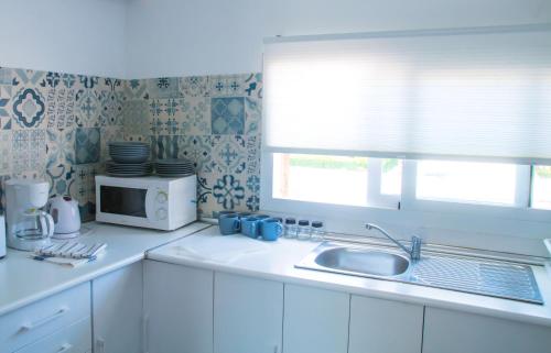 eine weiße Küche mit einer Spüle und einer Mikrowelle in der Unterkunft D’AGOSTA Beach Apartment in Alcúdia