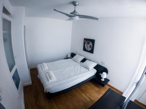 Bett in einem Zimmer mit Deckenventilator in der Unterkunft D’AGOSTA Beach Apartment in Alcúdia