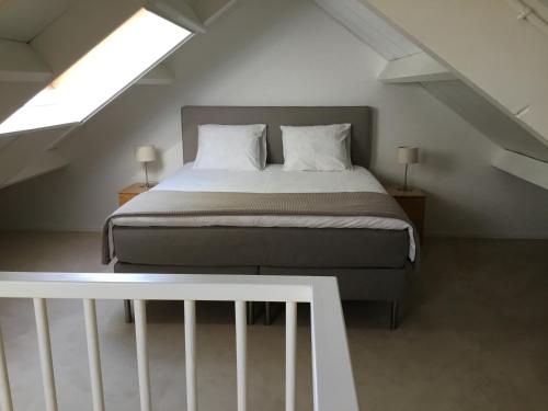 a bedroom with a bed in a attic with two lamps at Gastenverblijf WeijdeBlik in Sinderen