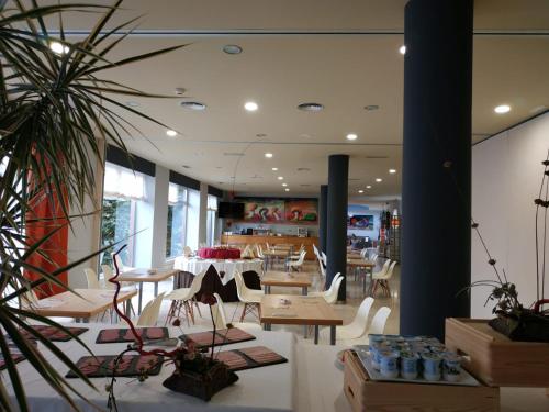 a restaurant with tables and chairs and a cafeteria at Hotel Arha Mar Comillas in Comillas