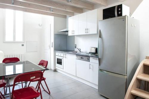 une cuisine avec des armoires blanches et un réfrigérateur en acier inoxydable dans l'établissement Les Beaux Rivages - Superbe T1 bis de 35 m2 - stationnement gratuit - proche gare et port - Apt Gauche, à La Rochelle