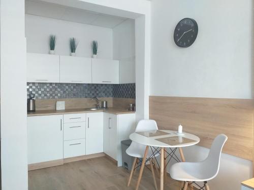 Figaro Apartaments في غدينيا: مطبخ مع دواليب بيضاء وطاولة وكراسي