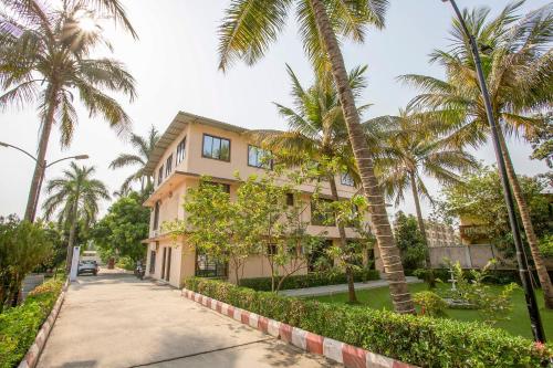 a building with palm trees on the side of a street at Pushp Vatika Resort & Lawns in Navi Mumbai