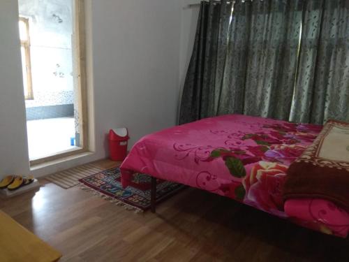 a bedroom with a pink bed and a window at Chosdup Guest House in Leh