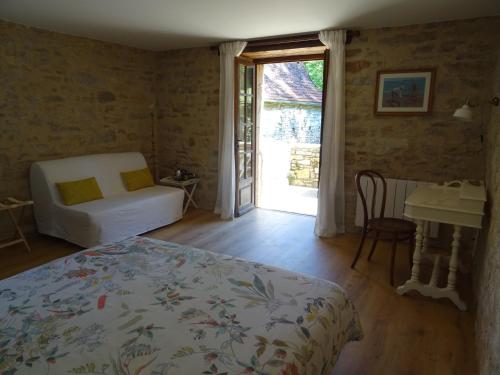 a bedroom with a bed and a table and a window at La Terralha in Saint-Pierre-Toirac
