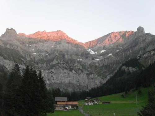 a group of mountains with a green field and houses at Chalet Bunderbach in Adelboden