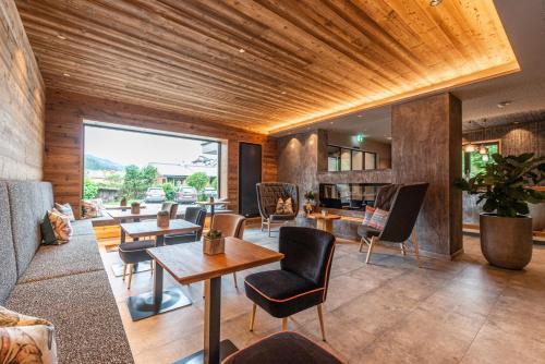 a living room with wooden ceilings and tables and chairs at Stadtvilla Schladming Boutiquehotel in Schladming