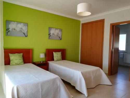 2 łóżka w pokoju z zielonymi ścianami w obiekcie Villa 48 w mieście Quarteira
