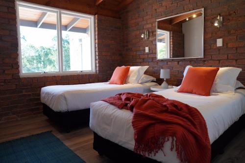 two beds in a room with a brick wall at McCarthy Grove Maleny in Maleny