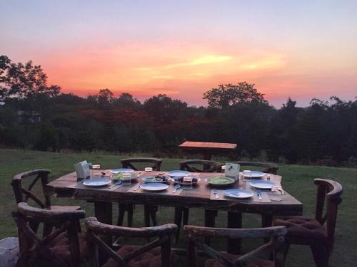 a wooden table with chairs around it with a sunset at Khaoyai Nature Retreat in Baan Wang Mi