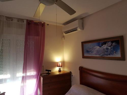 1 dormitorio con 1 cama y ventana con ventilador en Bajo con jardin WIFI junto al mar, en Playas de Orihuela