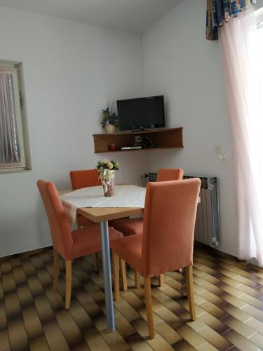 a dining room table with orange chairs and a television at Apartments Merica in Novalja