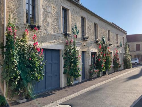 a building with flowers on the side of a street at JunoGîte - Résidence in Bernières-sur-Mer
