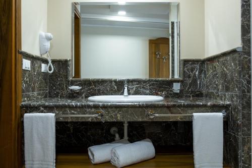 W łazience znajduje się umywalka, lustro i ręczniki. w obiekcie Hotel Panoramic w mieście Giardini Naxos