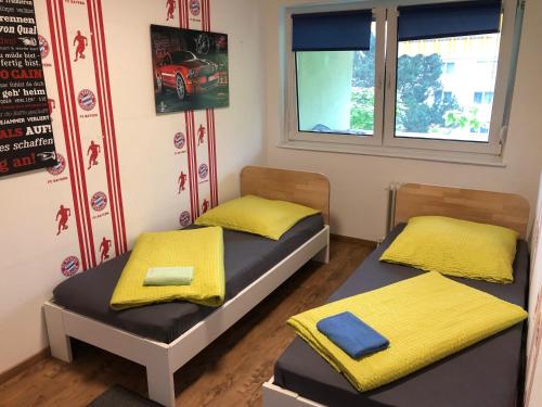 2 Betten in einem Zimmer mit gelber Bettwäsche und einem Fenster in der Unterkunft Ferienwohnung Mainz-Bretzenheim in Mainz