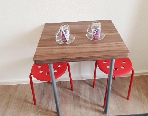 una mesa de madera con 2 sillas y 2 vasos. en Komfort Ferienwohnungen Zwenkauer See, en Zwenkau