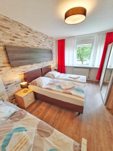 a bedroom with two beds and a brick wall at Komfort Ferienwohnungen Zwenkauer See in Zwenkau
