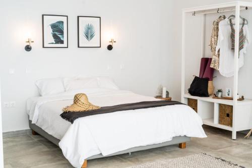 a white bedroom with a bed and a shelf with clothes at SECRET HILL in Athani