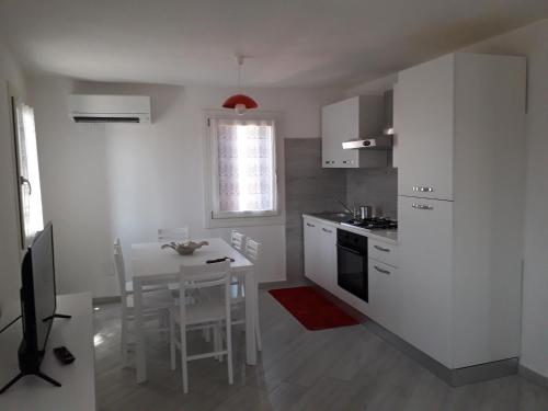 une cuisine avec des placards blancs et une table avec une salle à manger dans l'établissement ANGOLO DI LUCE, à Chioggia