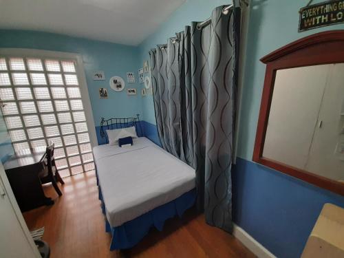 a small bedroom with a bed in a blue room at Old Orangewood Bed & Breakfast in Baguio