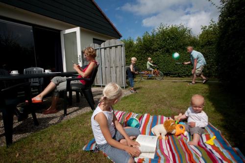 a group of people sitting on a blanket in the yard at Vakantiepark Dennenoord in Den Burg