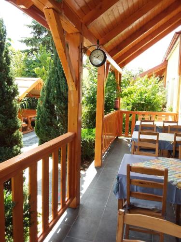 une terrasse en bois avec des tables et une horloge. dans l'établissement Szentesi Panzió, à Fertőrákos