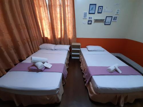 three beds sitting in a room with curtains at Old Orangewood Bed & Breakfast in Baguio