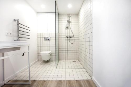 een witte badkamer met een douche en een toilet bij G - Owl Jazz -Modern loft type apartment 18 with big roof terrace and free private parking in Kaunas