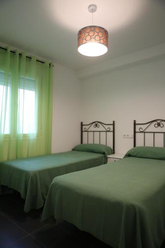 a room with two beds with green sheets and a light at APARTAMENTOS LA VEREDA in Cuenca