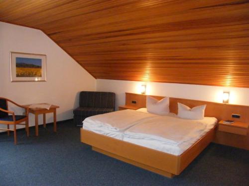 a hotel room with a bed and a chair at Gasthaus Hotel Pfeifferling in Wolfhagen