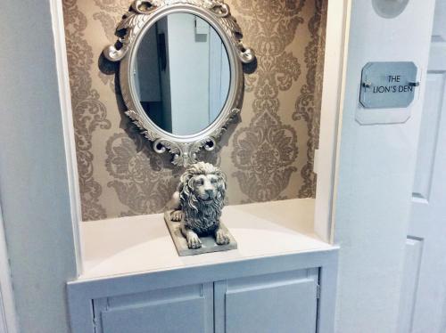a mirror on top of a dresser with a lion statue at THE LION'S DEN ON ROYAL STREET in Gourock