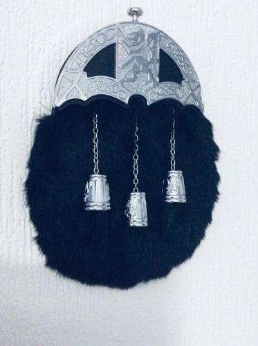 a chandelier with three bells hanging on a wall at THE LION'S DEN ON ROYAL STREET in Gourock