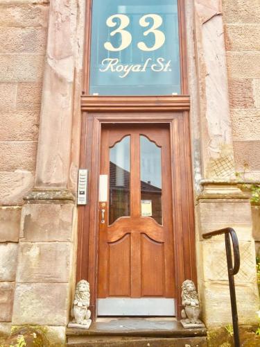 a wooden door on a building with a sign above it at THE LION'S DEN ON ROYAL STREET in Gourock