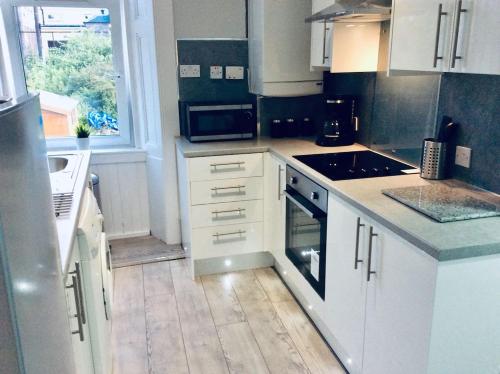 a kitchen with white cabinets and a stove top oven at THE LION'S DEN ON ROYAL STREET in Gourock