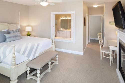 a bedroom with a white bed and a television at Inn at Harbor Hill Marina in Niantic