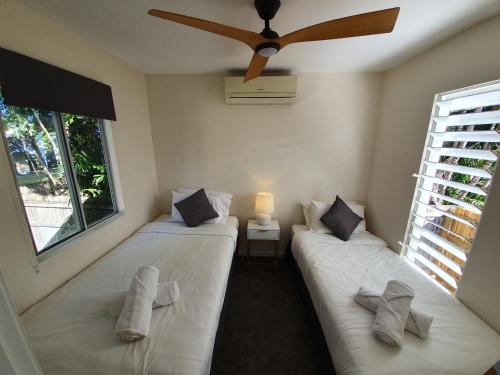 two beds in a room with a ceiling fan at Cosy 2 bedroom home in Townsville