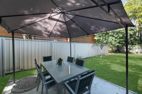 a patio with a table and chairs under a black canopy at Cosy 2 bedroom home in Townsville