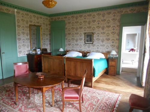 - une chambre avec un lit, une table et des chaises dans l'établissement Le Château d'Ailly, à Parigny