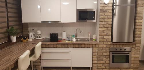 a kitchen with white cabinets and stainless steel appliances at Duna Dráva Vendégház in Érsekcsanád