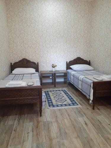 two beds in a room with wooden floors at Apartments on Akhalubani St 2 in Tbilisi City