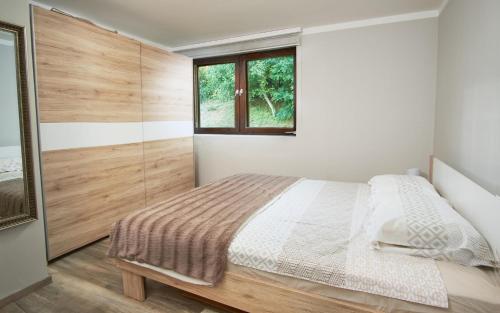 a white bedroom with a bed and a window at Family Retreat with Pool, BBQ & Green Escape by Destination GREEN Croatia in Praporčan