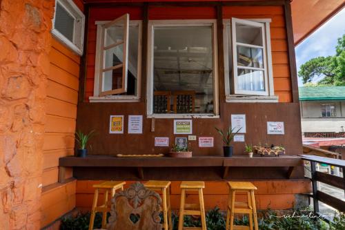 a house with two stools and two windows at Old Orangewood Bed & Breakfast in Baguio
