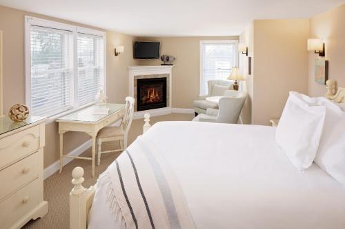 a bedroom with a bed and a desk and a fireplace at Inn at Harbor Hill Marina in Niantic