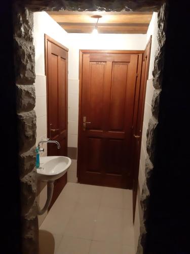 a bathroom with a sink and a wooden door at Robinson camp "Zeleni mir" in Josipdol