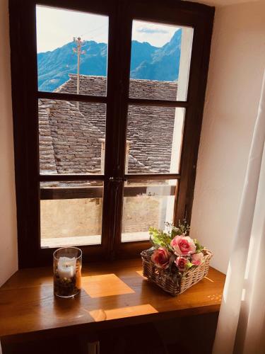 a window with a basket of flowers and a candle at Casa Ruscada in Borgnone