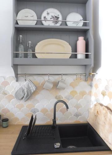 a kitchen with a sink and plates on a shelf at Apartament Pod Tężnią in Głuchołazy