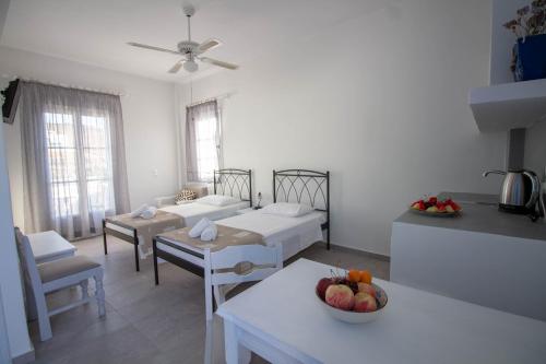 a room with two beds and a table with a bowl of fruit at Meltemi Hotel Kythnos in Loutra