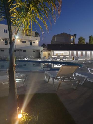 a pool with a table and chairs and a palm tree at Sibari Residence in Marina di Sibari